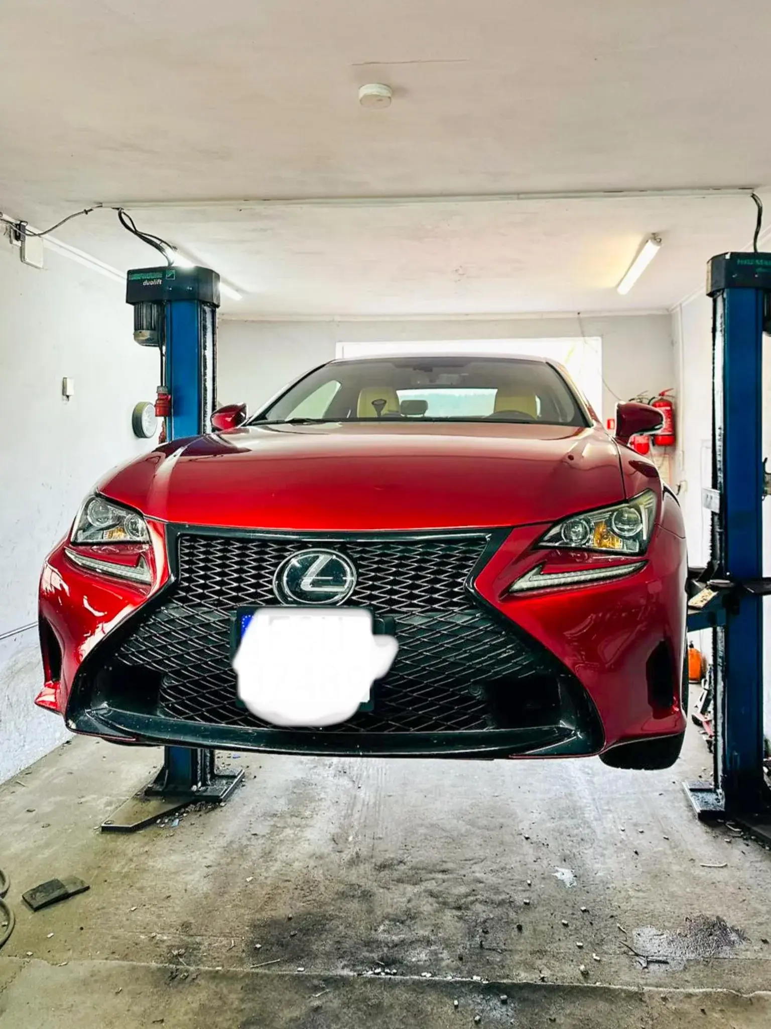 Czerwony Lexus na podnośniku dwukolumnowym w warsztacie
