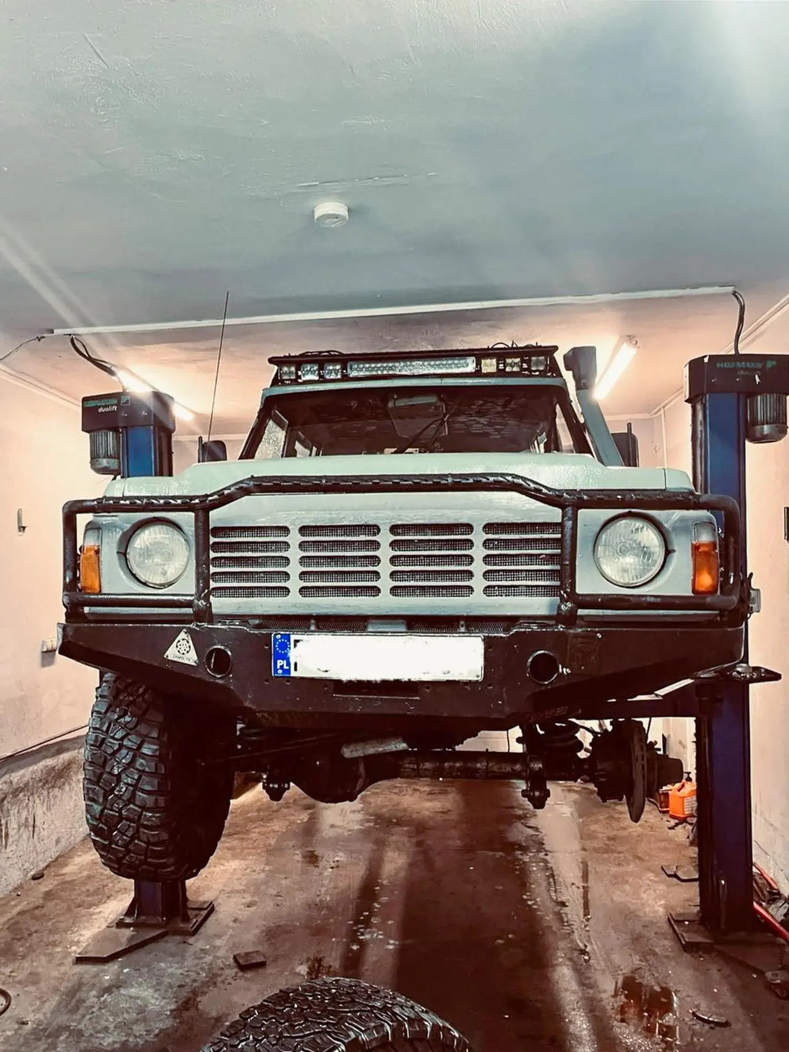 Terenowe auto na podnośniku w trakcie prac warsztatowych