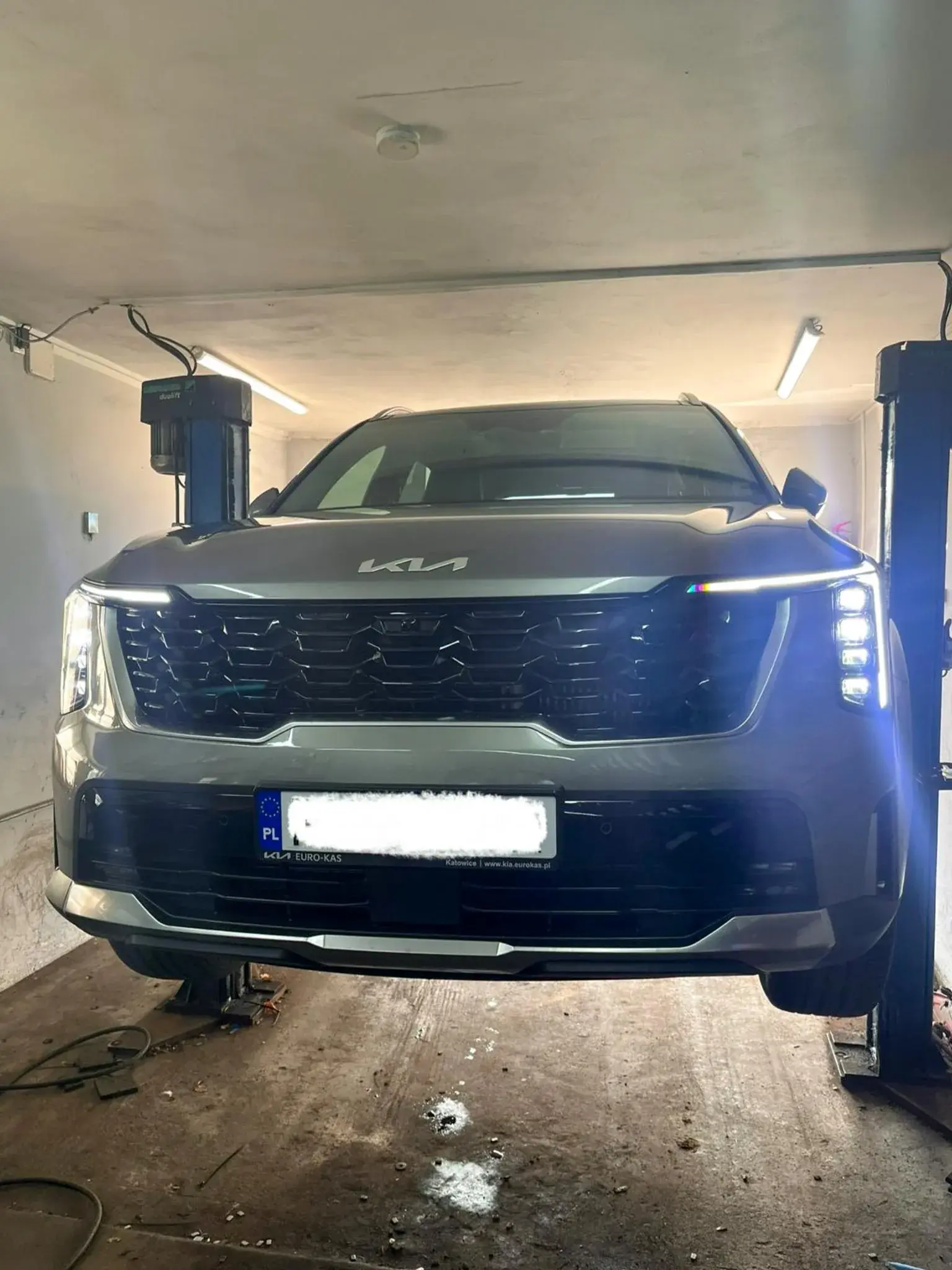 Szary SUV Kia na podnośniku podczas serwisu opon