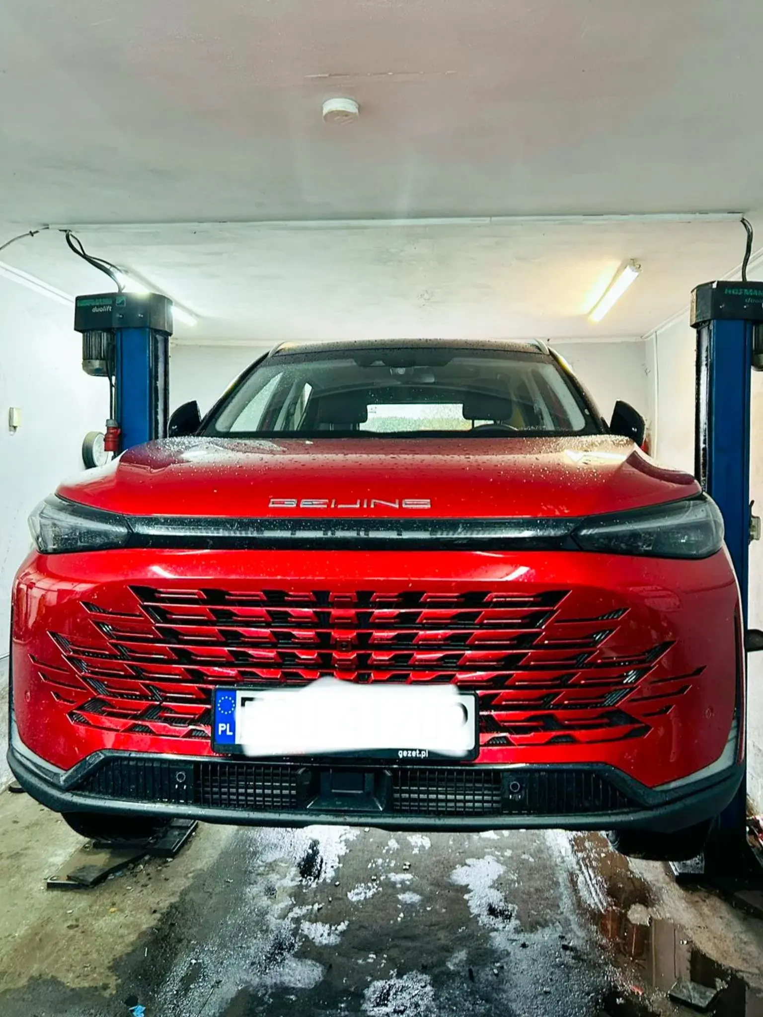 Czerwony SUV na stanowisku serwisowym po wymianie kół