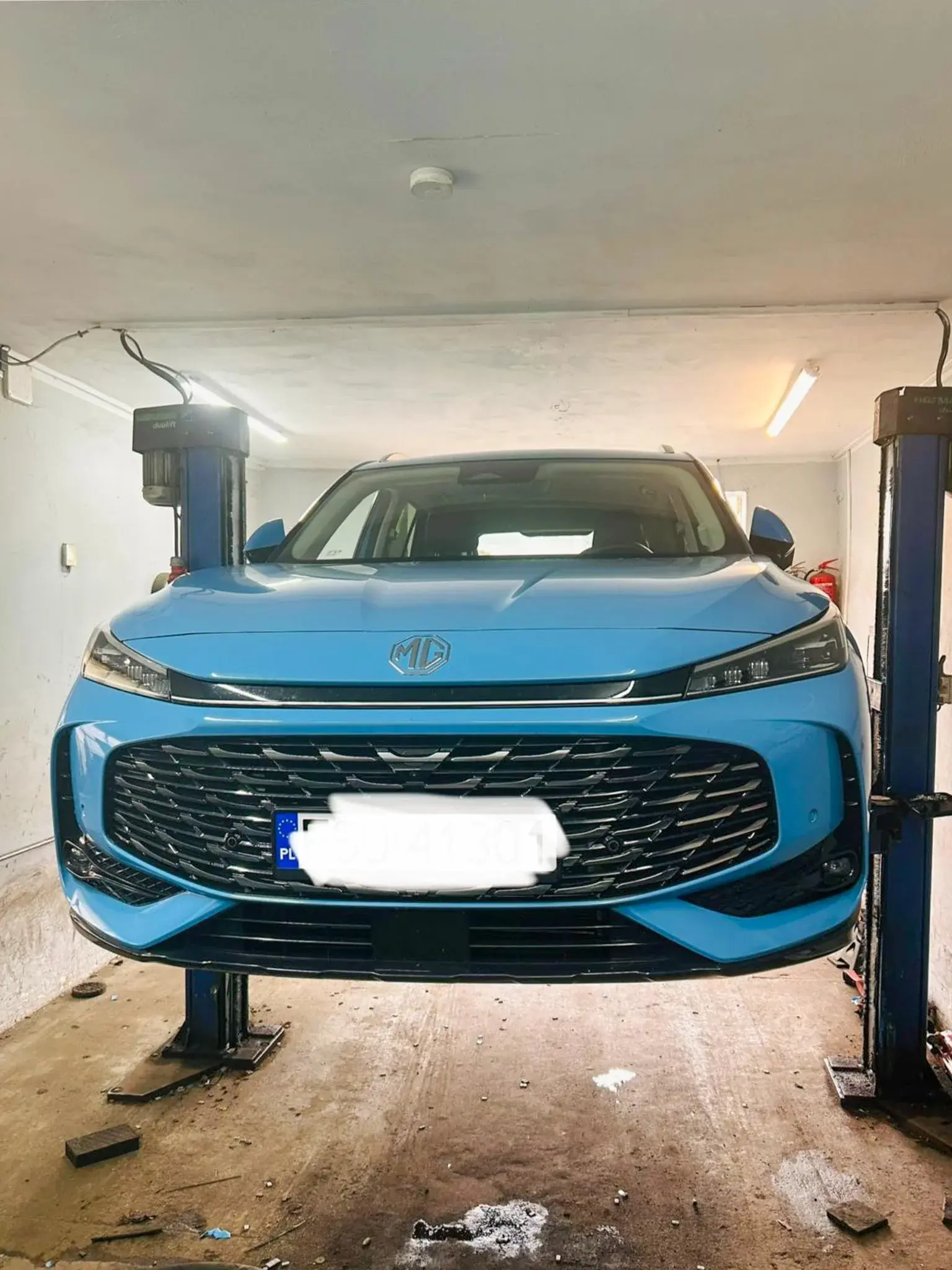 Niebieskie MG na podnośniku w warsztacie wulkanizacyjnym