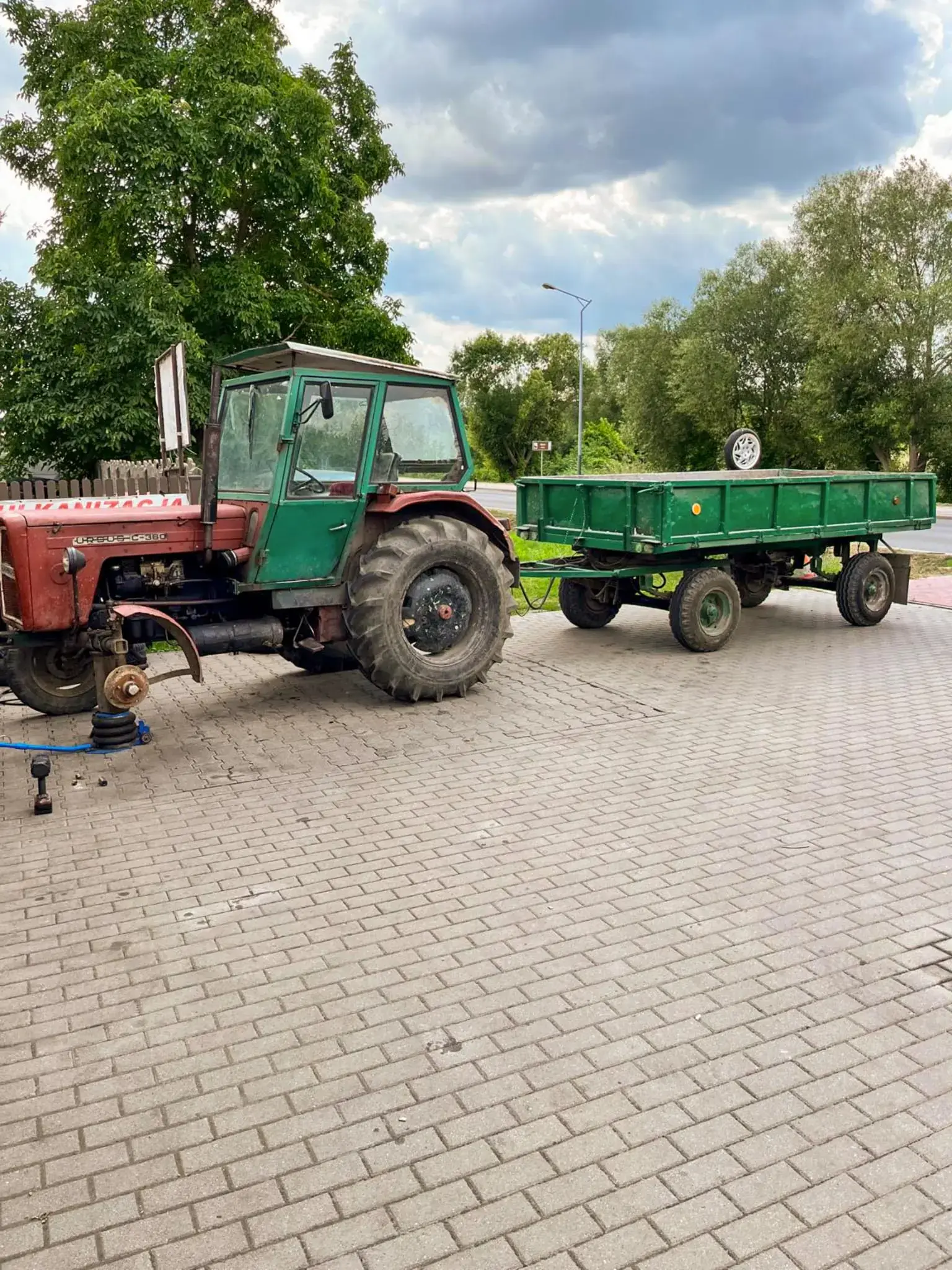 Ciągnik z przyczepą podczas pracy serwisowej przy kole